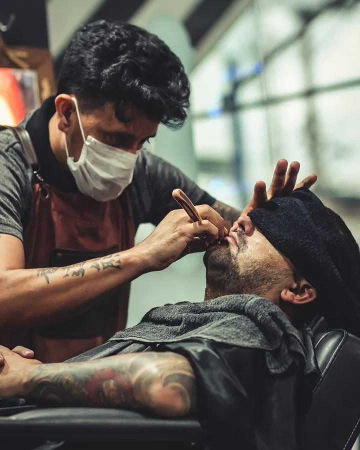 Barbero arreglando la barba a un cliente