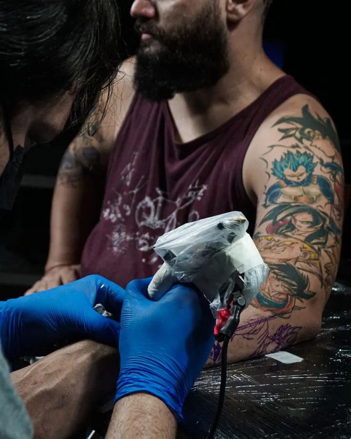 Tatuador trabajando en el brazo de un cliente